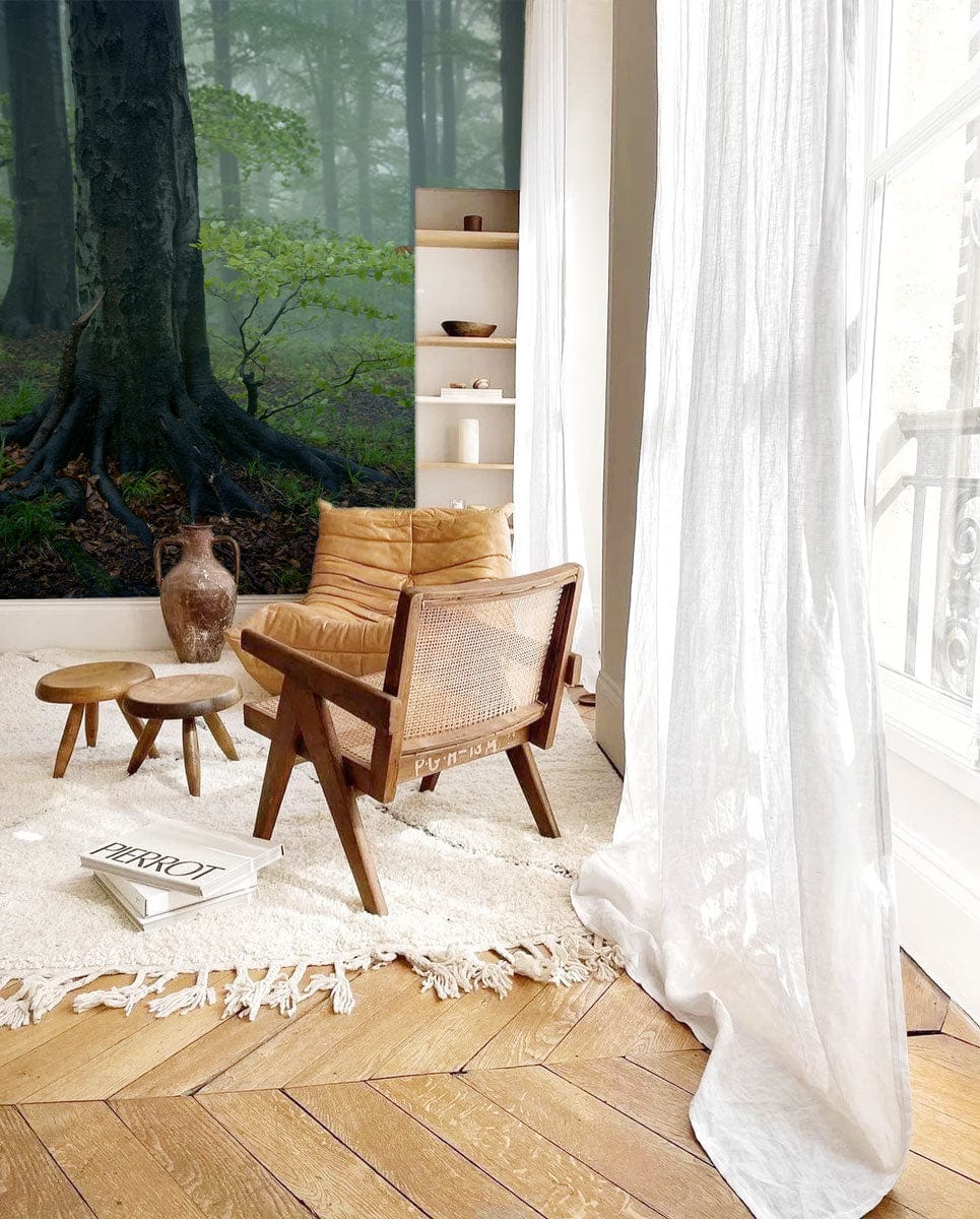 Enchanted Misty Forest Mural Wallpaper in cosy living room, with tan chair, wooden floor, white curtains.