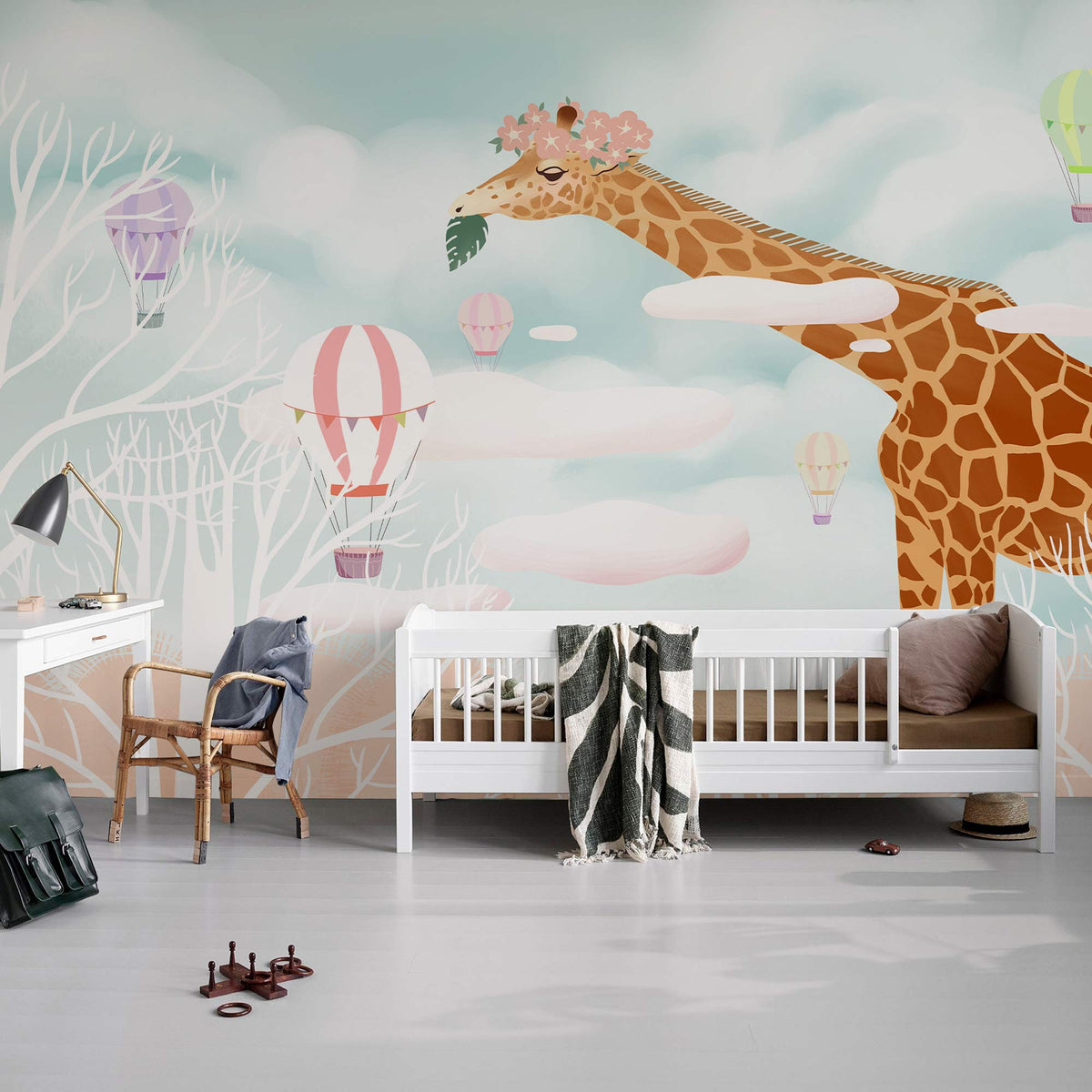Children's room with Whimsical Giraffe mural, pastel hot air balloons, white furniture, and grey flooring.