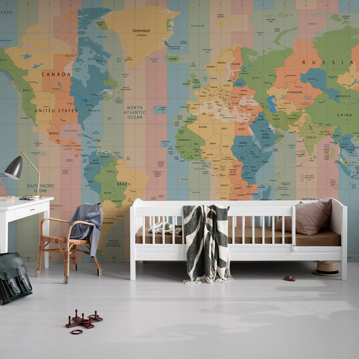 Educational World Map Mural Wallpaper in soft pastels, featuring white child's bed, wooden chair.