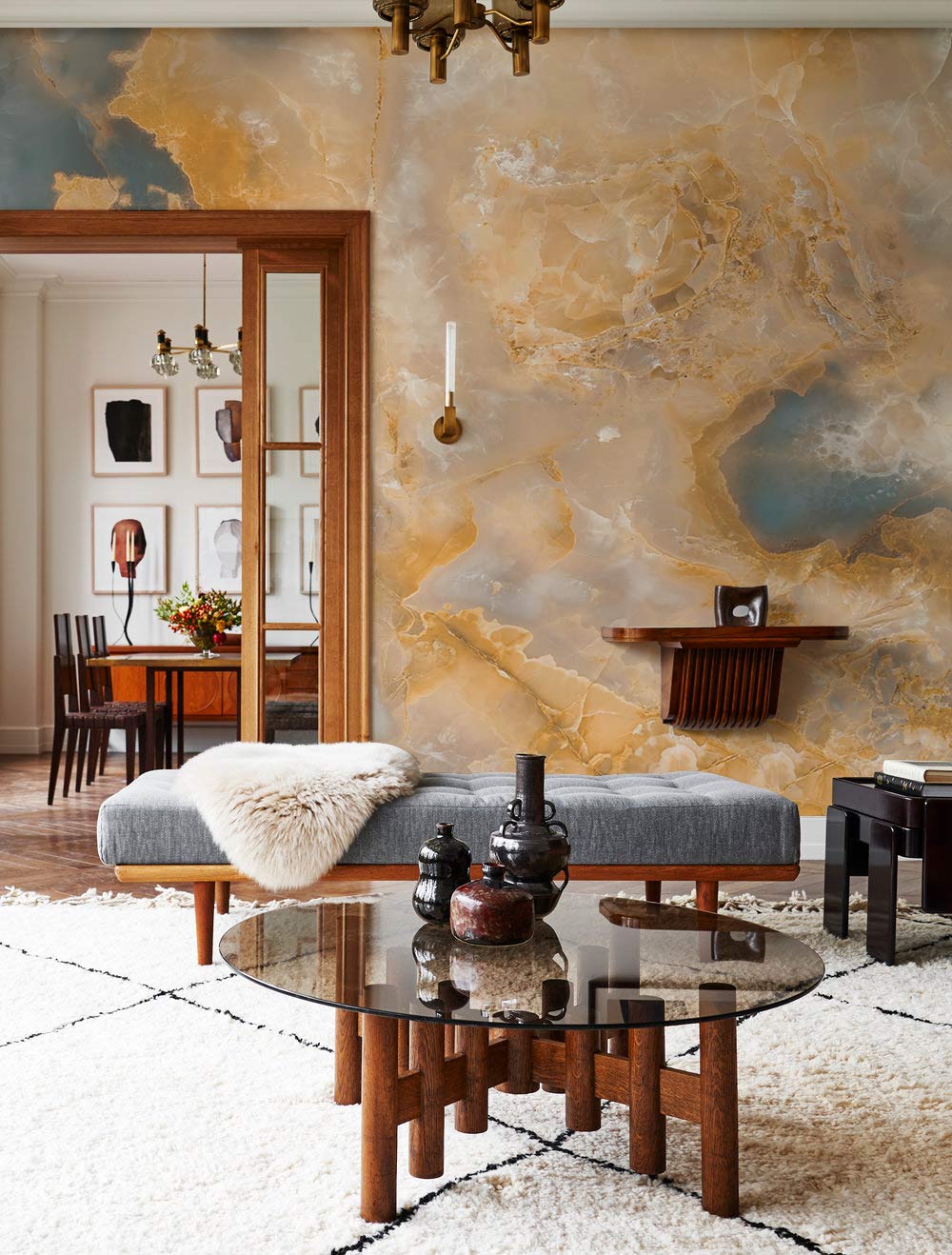 Golden Marble Dream Luxe Onyx Wallpaper in living room with grey sofa, glass table, and warm tones.