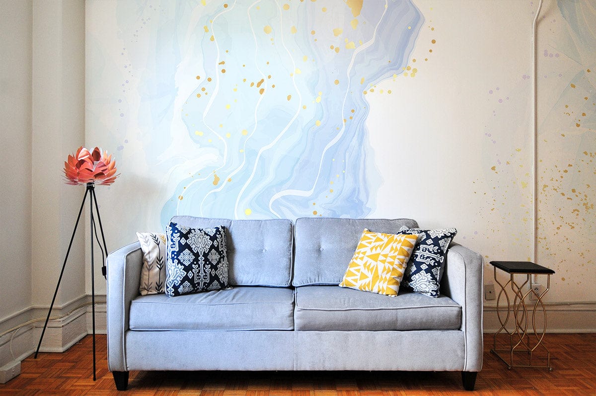 Elegant blue and gold abstract wall mural with grey sofa, parquet flooring, and modern tripod lamp.
