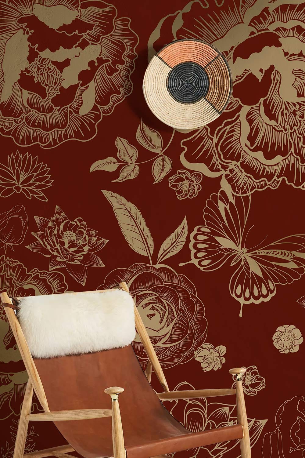 Elegant burgundy floral wallpaper with gold accents, stylish chair, woven wall decor, modern room design.