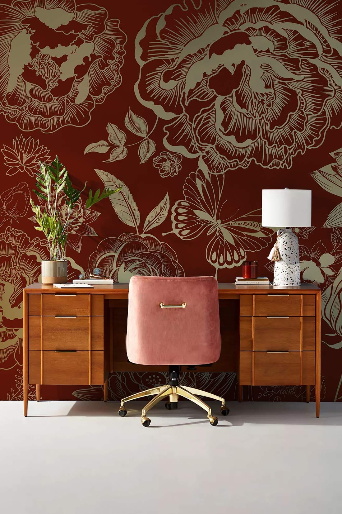 Elegant burgundy wallpaper with gold accents, wooden desk, pink chair, ideal for home office.