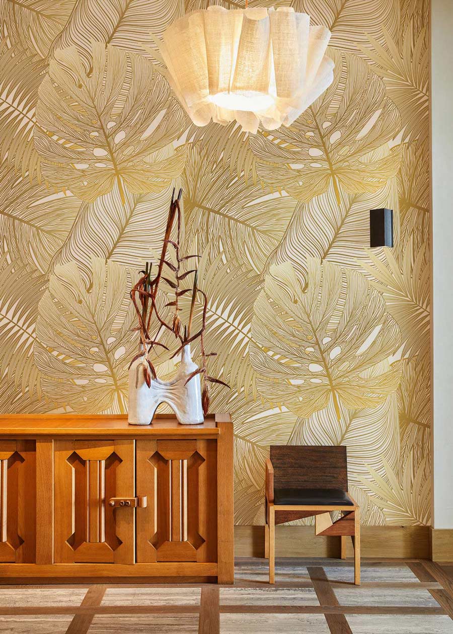 Elegant gold tropical leaf wallpaper with chic botanical design, wooden sideboard, chair, stylish pendant lamp.