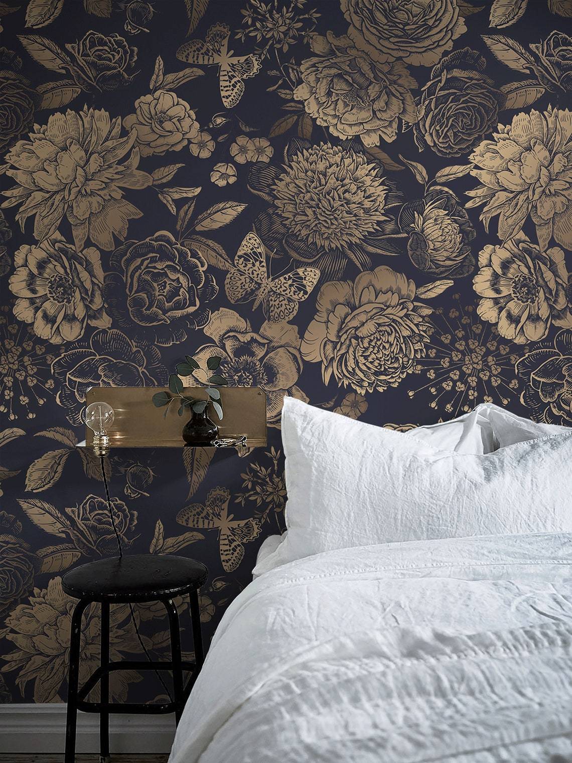 Luxurious gold floral damask wallpaper with elegant navy background, white bedding, and stylish stool.