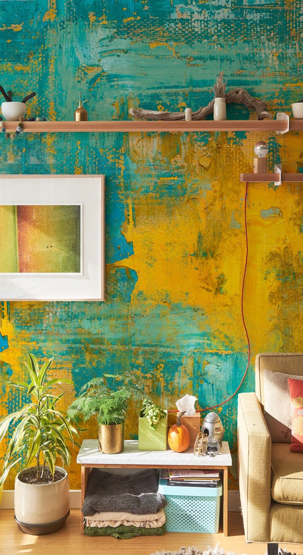 Colourful abstract teal yellow mural wallpaper, neutral sofa, light wood floor, modern living room decor.