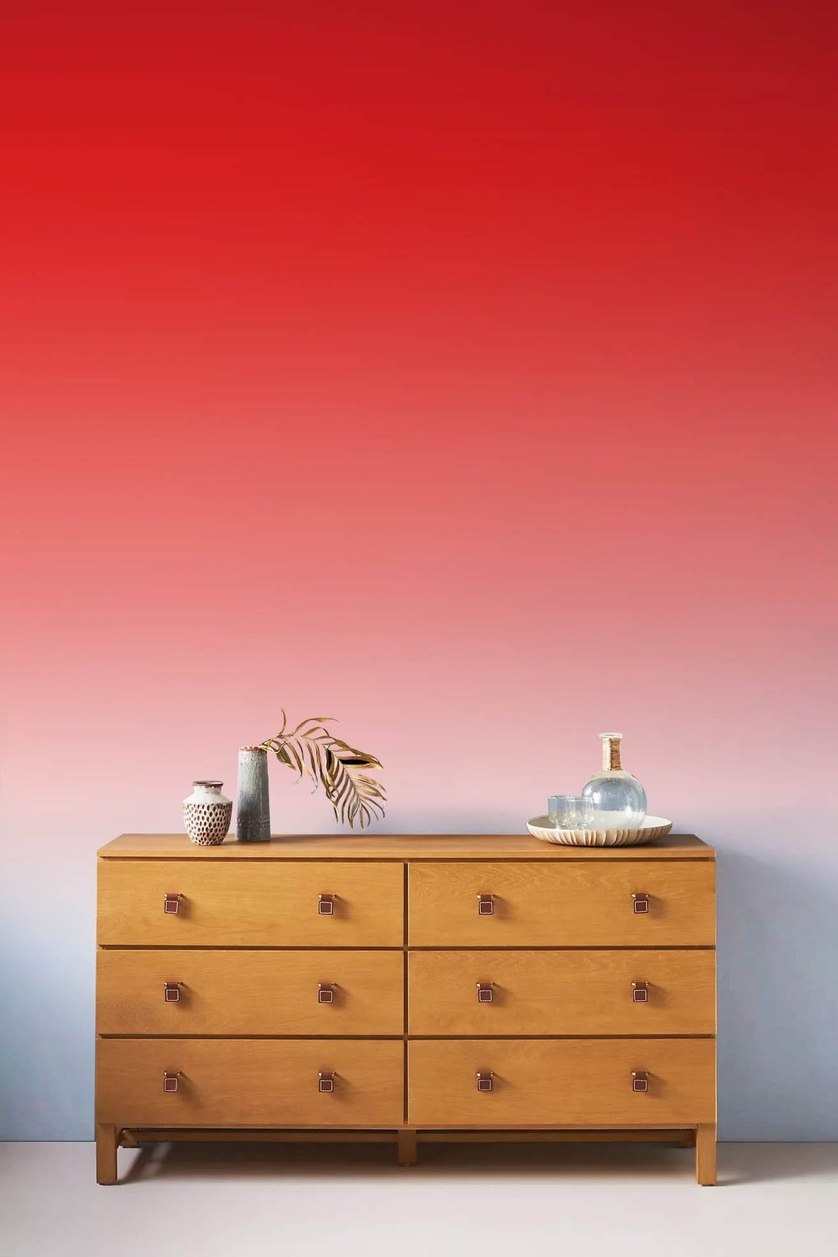 Vibrant ombre wallpaper with wooden dresser, ideal for stylish modern interiors.