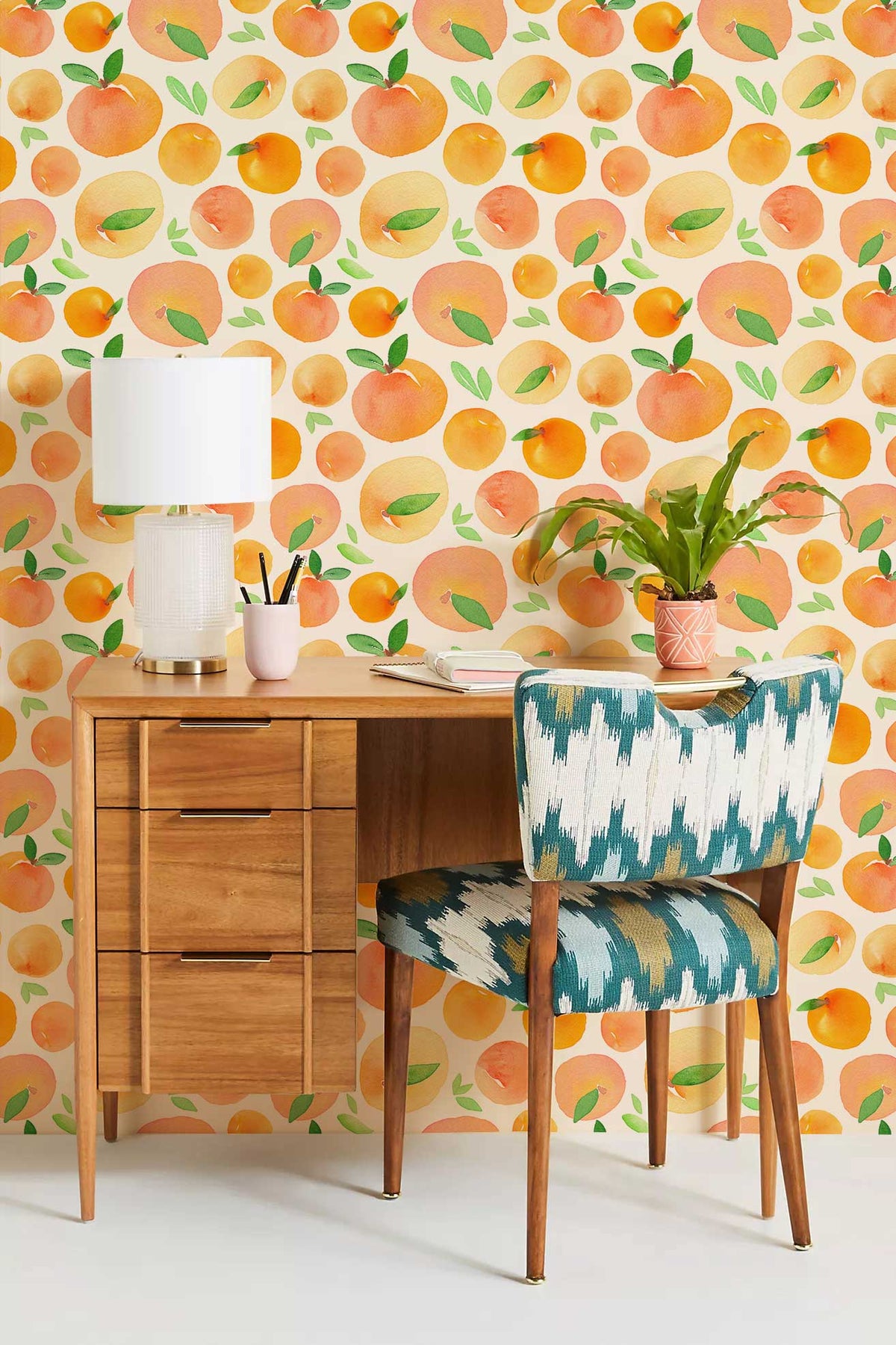 Peachy orange fruit mural wallpaper, wooden desk, patterned chair, modern lamp, home office decor.