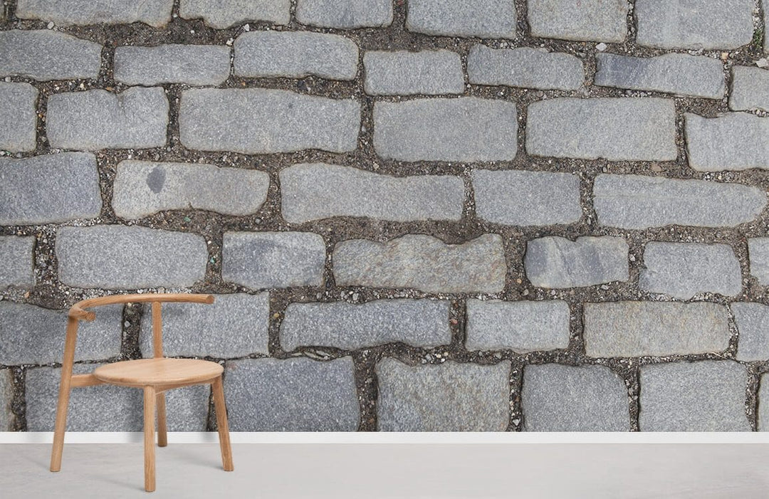 Rustic grey cobblestone wallpaper with wooden chair, complements vintage stone decor in modern room setting.