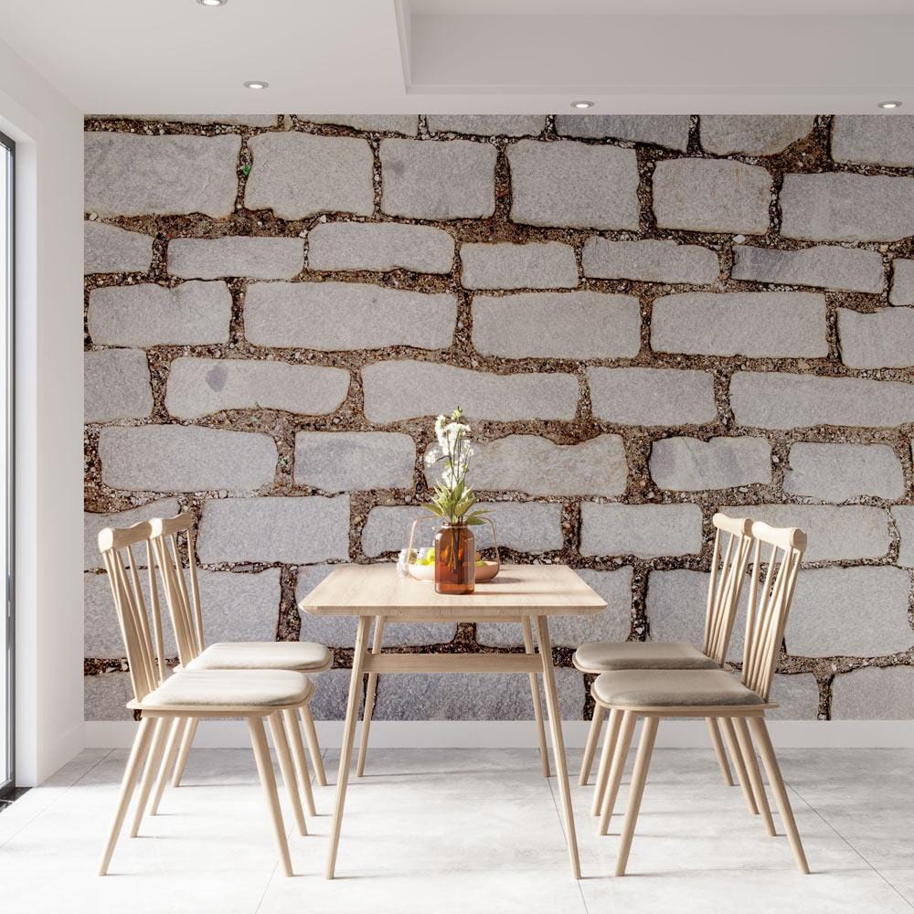 Rustic Grey Cobblestone Wallpaper in dining room with wooden table, chairs, and light stone flooring.