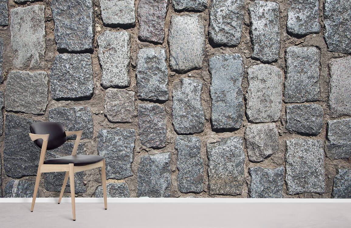 Rustic cobblestone wallpaper in natural grey tones; features modern black chair; beige flooring.