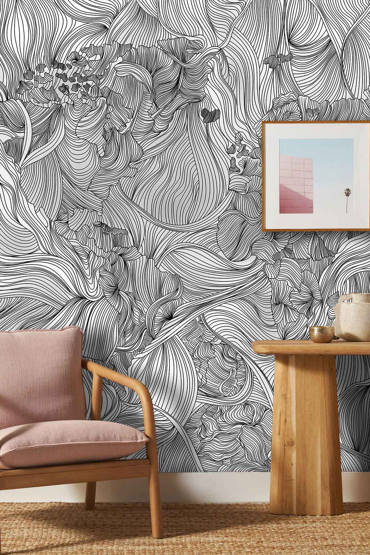 Monochrome Floral Fantasy wallpaper in living room with pink chair, wooden table, framed artwork.