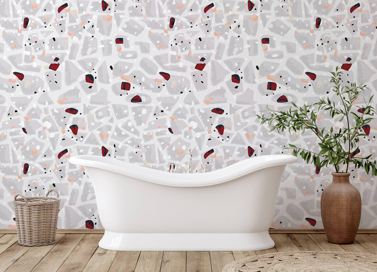 Contemporary abstract terrazzo wallpaper in bathroom with freestanding white tub and wooden flooring.