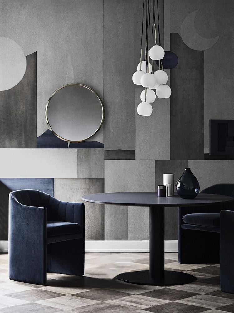 Contemporary dining room featuring geometric mural wallpaper, dark velvet chairs, round table, and pendant lighting.