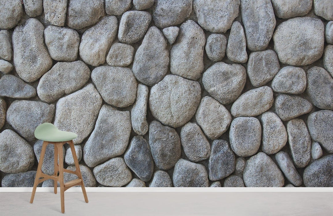 Rustic stone effect wallpaper mural, grey pebble pattern, featuring bar stool, light wood flooring.