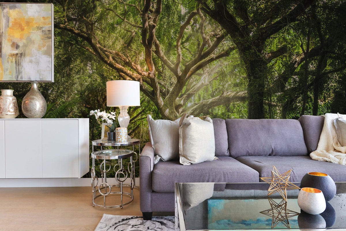 Forest green tree mural wallpaper with grey sofa, glass coffee table, abstract artwork, and modern decor.