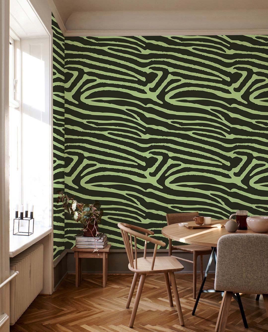 Modern green and black zebra wallpaper in dining room, wooden dining table, chevron-patterned flooring.