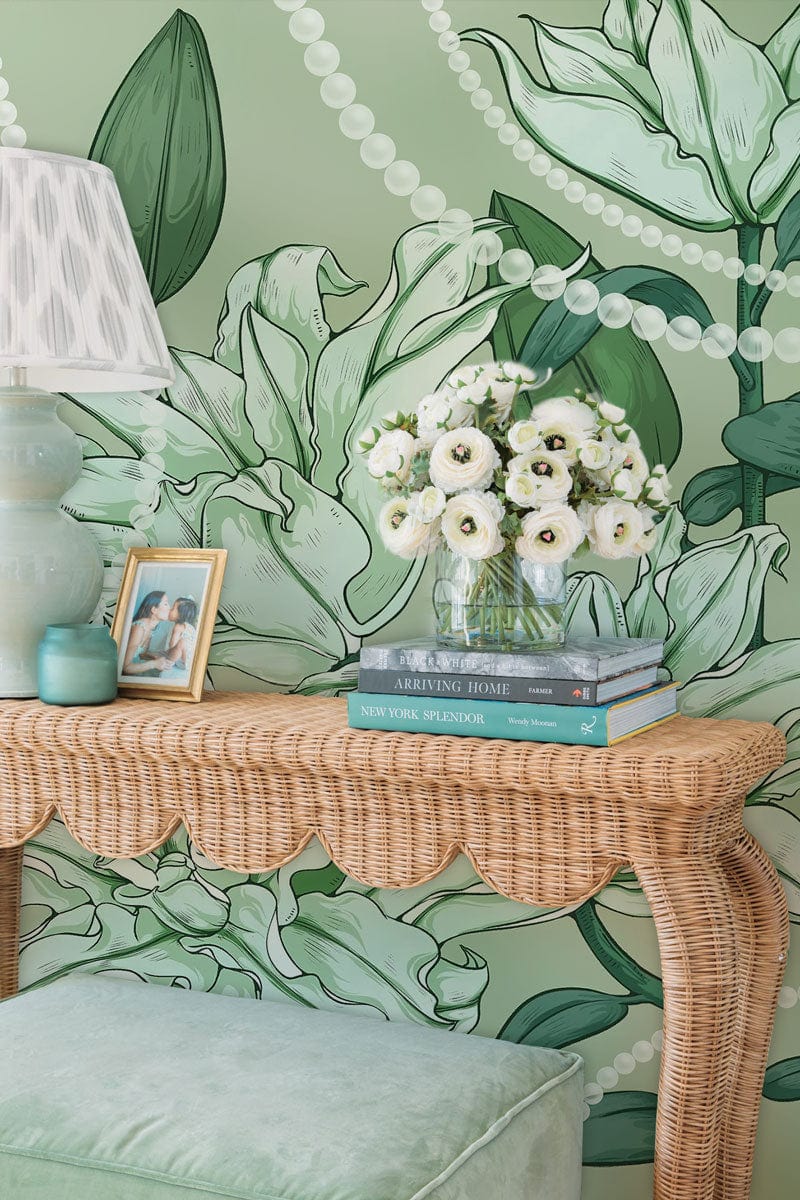 Elegant green floral wallpaper, pearl accents, wicker furniture, soft green cushion, stylish interiors.