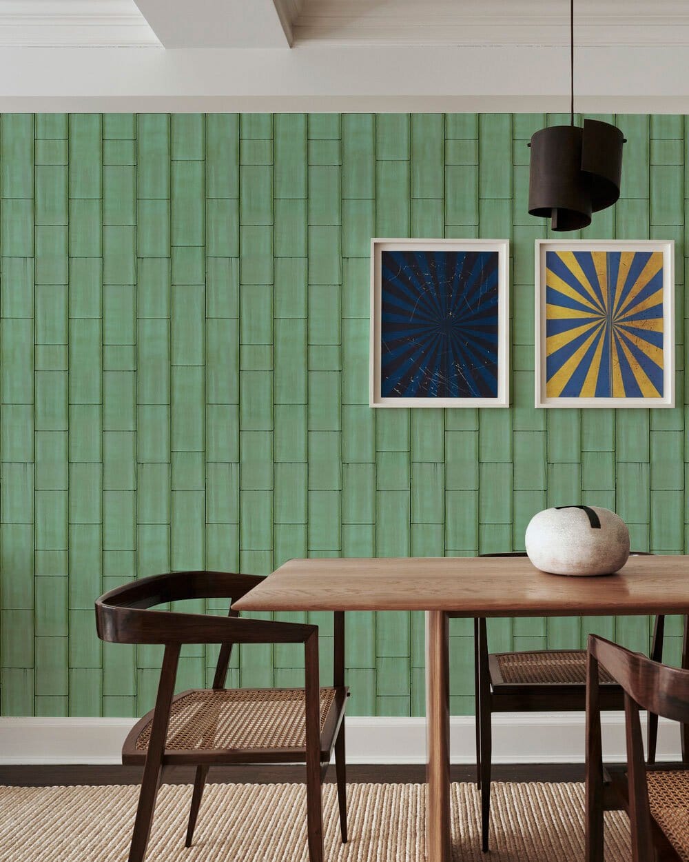 Teal wallpaper with geometric pattern, wooden dining table, woven chairs, minimalist decor, contemporary art.