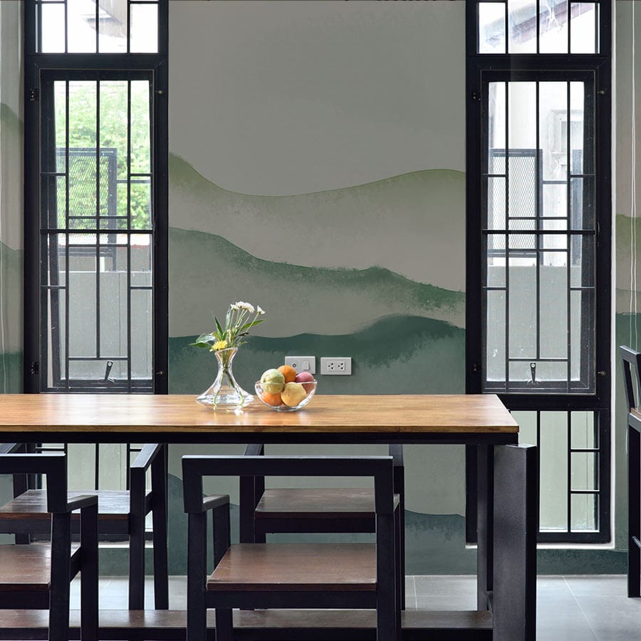 Dining room featuring Misty Mountain Serenity green watercolour mural wallpaper, wooden table, and black framed windows.