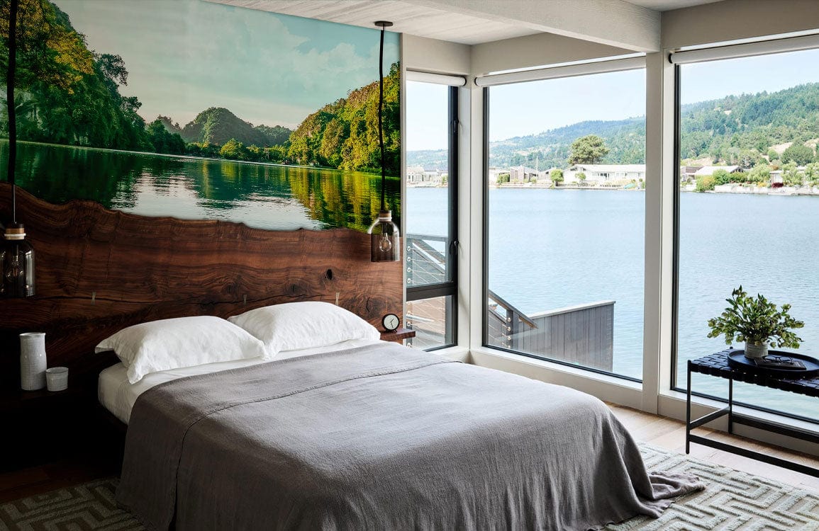 Bedroom with Tranquil Green Lake Reflection wall mural, grey duvet, hardwood floor, and lake view.