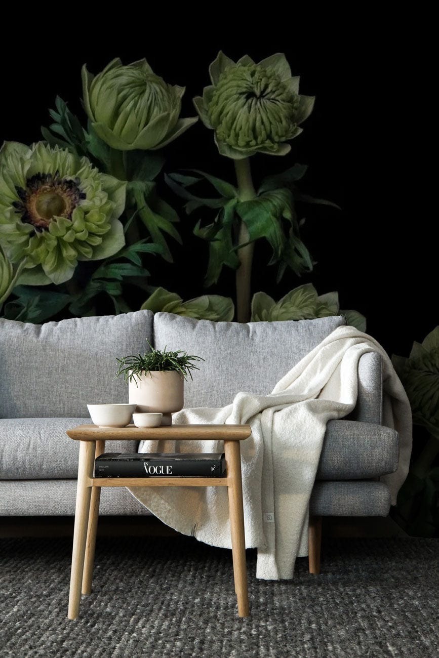 Green Floral Elegance wallpaper with grey sofa, wooden table, cosy throw, and dark botanical theme.