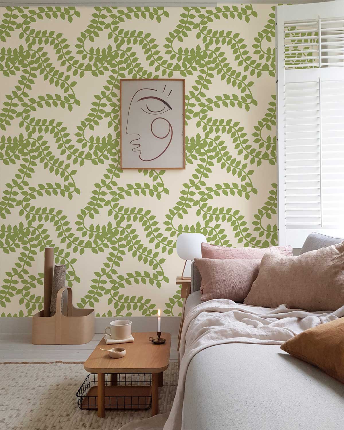 Green fern wallpaper in living room with beige sofa, wooden coffee table, and stylish wall art.