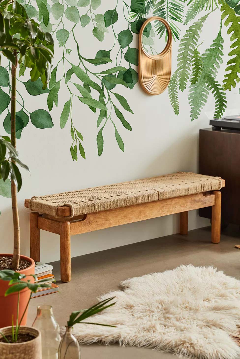 Lush Greenery Botanical Mural Wallpaper complements woven bench, cream rug, natural wood in serene setting.