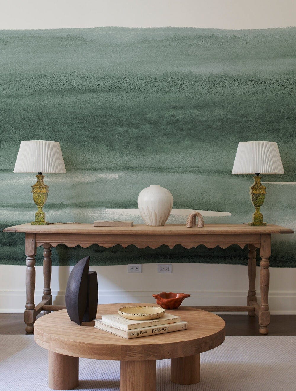 Tranquil Sage Green Watercolour Landscape Mural Wallpaper with wooden tables, elegant lamps, and neutral decor.