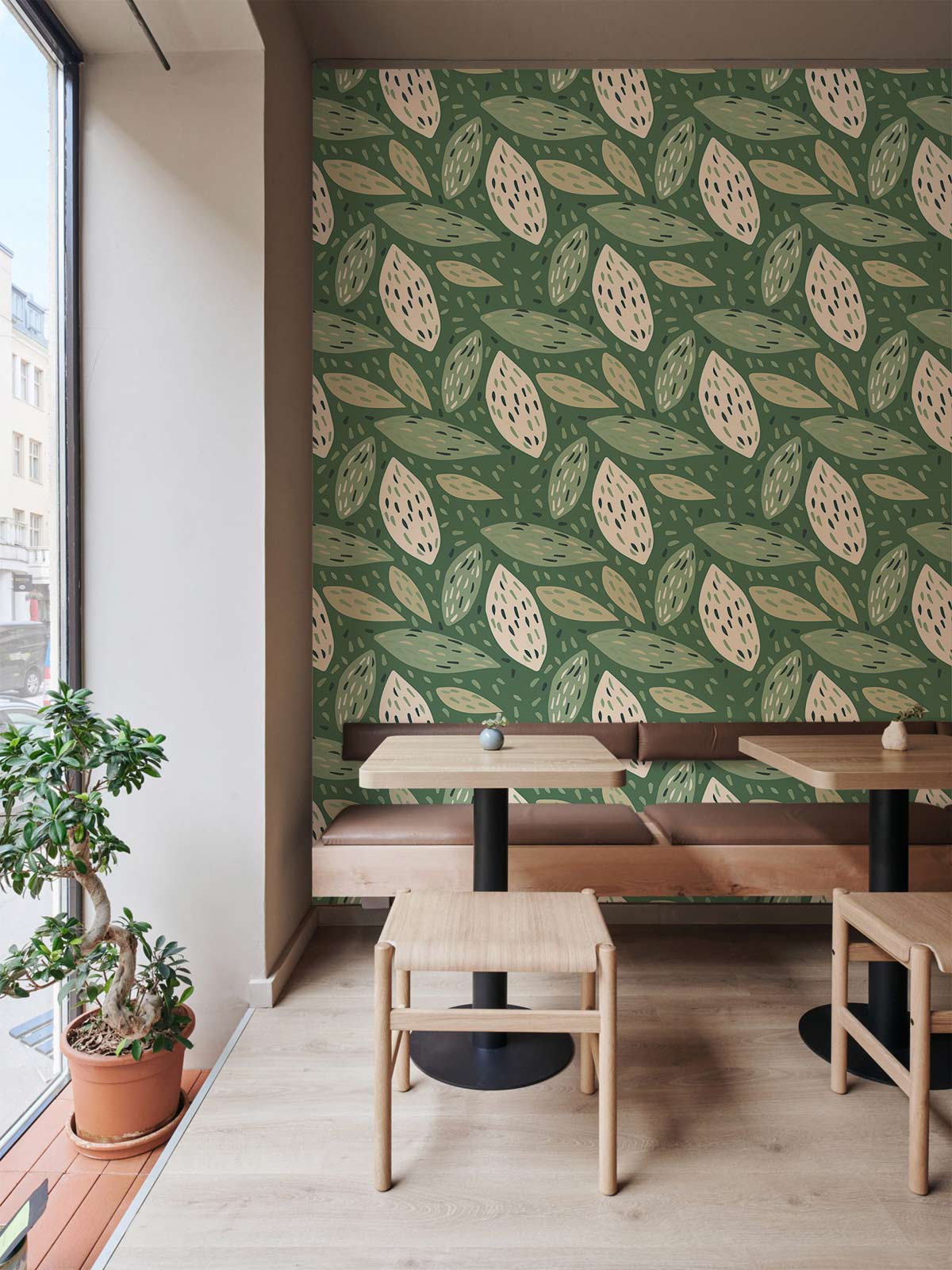 Botanical green leaf patterned wallpaper in cafe with wooden tables, beige walls, and light wood flooring.
