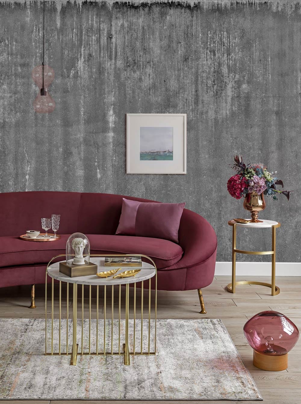 Industrial Chic Grey Concrete Textured Mural Wallpaper with Burgundy Sofa, Gold Tables, and Abstract Art.