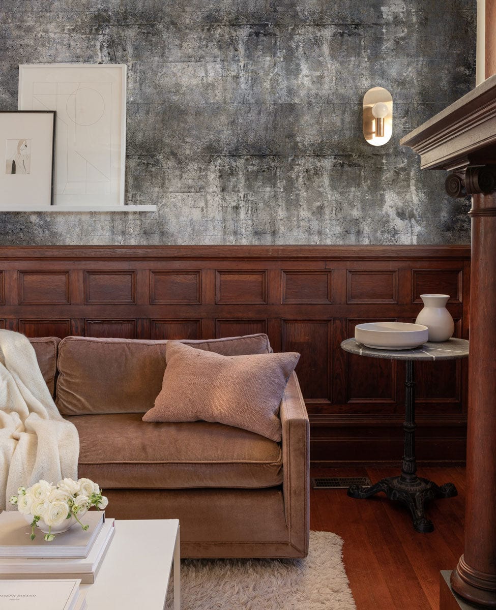 Industrial Chic wall mural with grey distressed concrete, brown sofa, wood paneling, round table, cosy room.