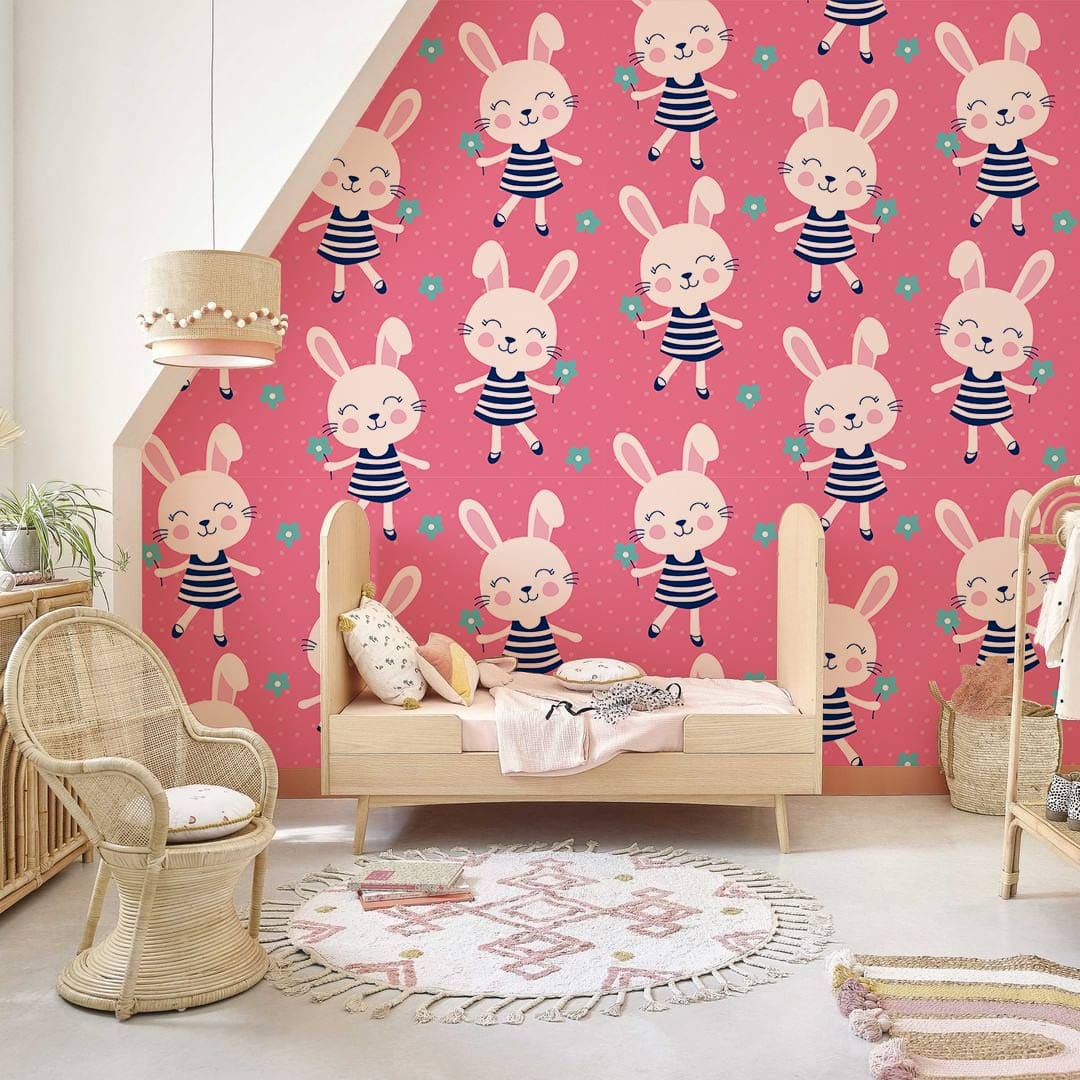 Children's room with pink bunny wallpaper, wicker furniture, neutral rug, and cosy Décor elements.
