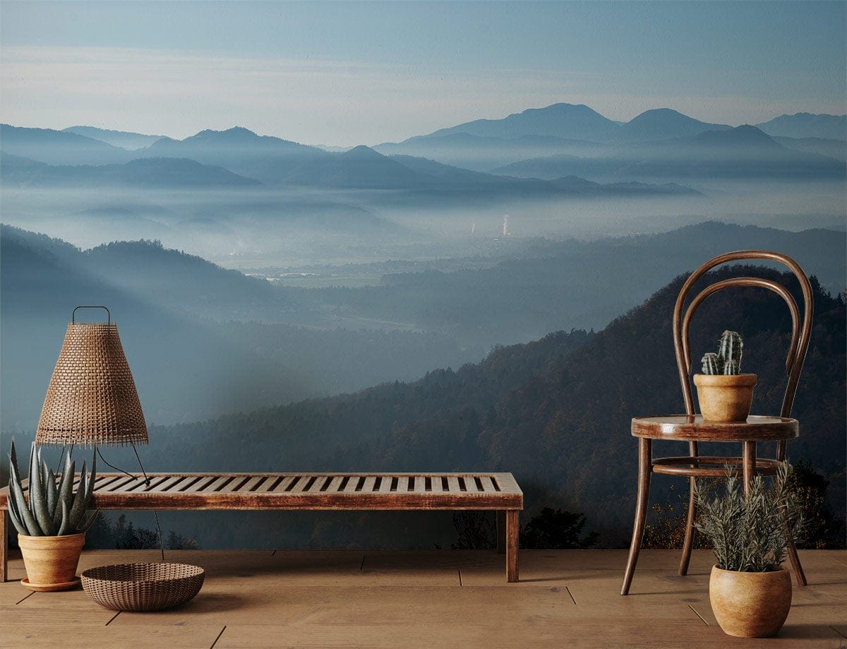 Serene Blue Mountain Mist Mural Wallpaper in rustic room, featuring wooden bench and wicker chair.