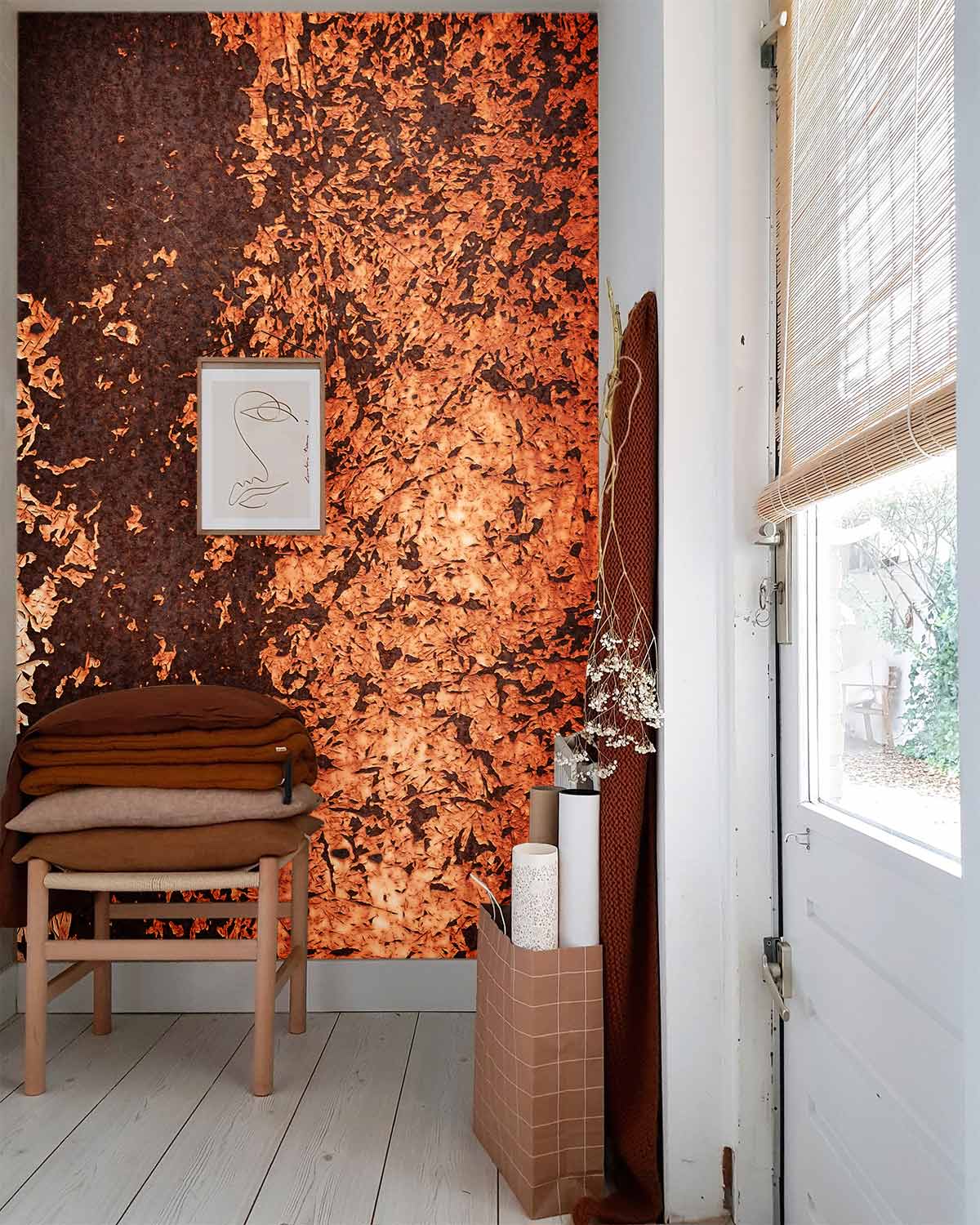 Rustic copper-textured wallpaper in bright room with white wood flooring, minimalist chair and blinds.