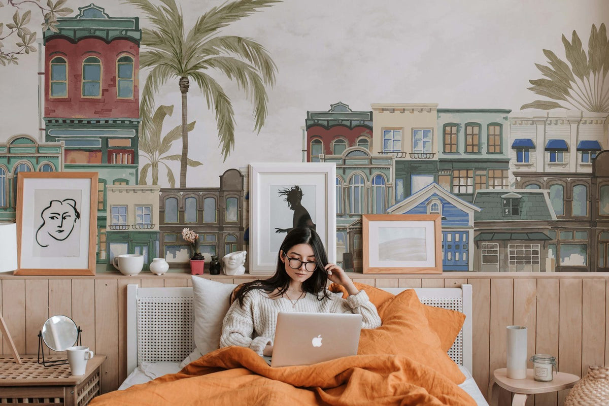 Vintage urban landscape mural wallpaper in pastel watercolour enhances cosy bedroom with orange bedding.