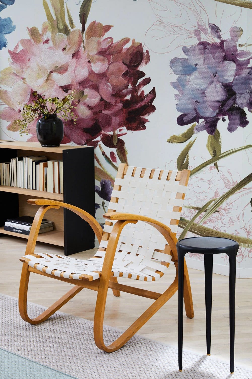 Elegant Floral Harmony Watercolour Hydrangea Mural, pastel blooms, woven chair, black side table, bookshelf.