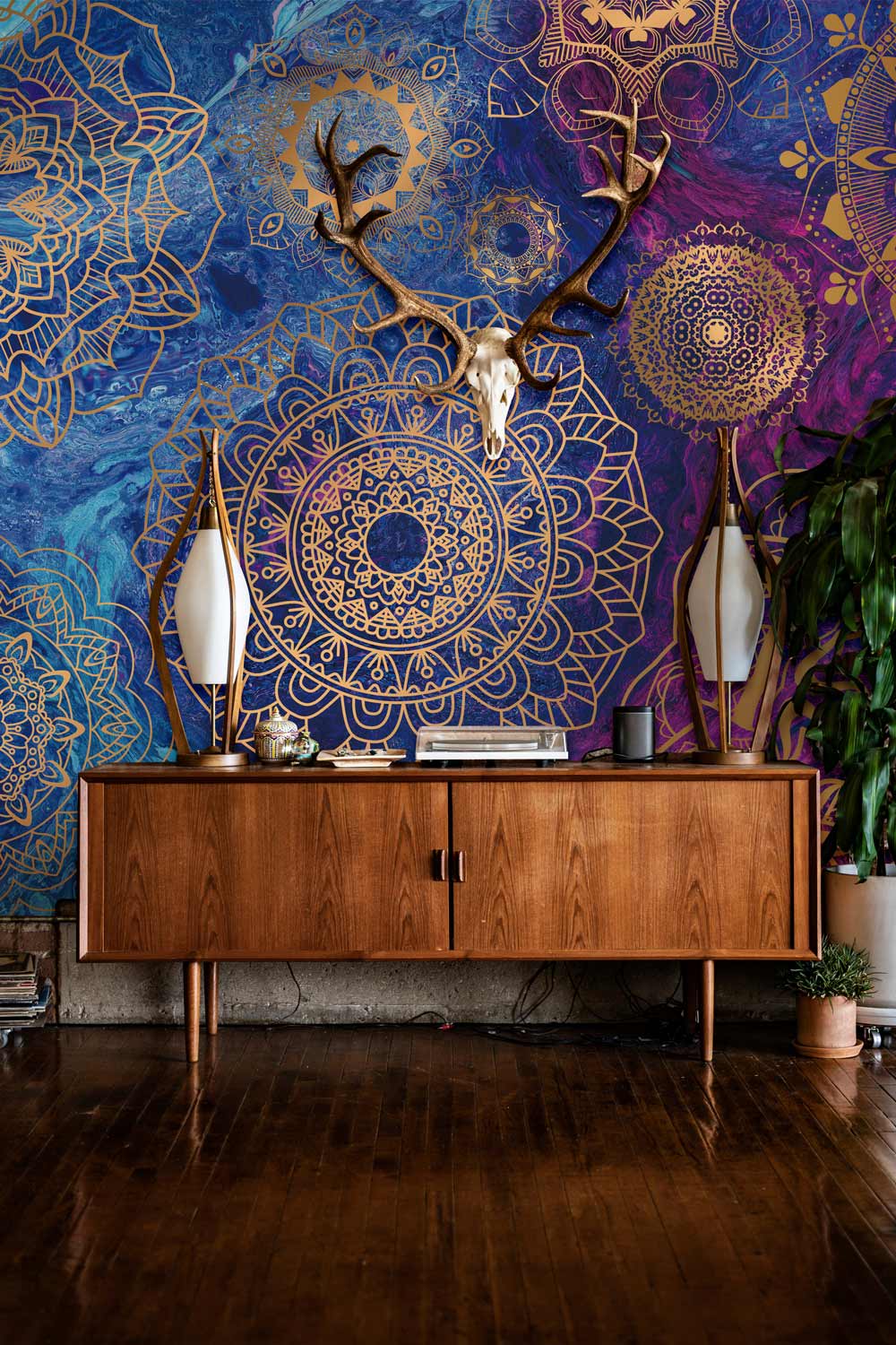 Elegant mandala wallpaper in gold, blue, and purple behind mid-century sideboard, wooden flooring.
