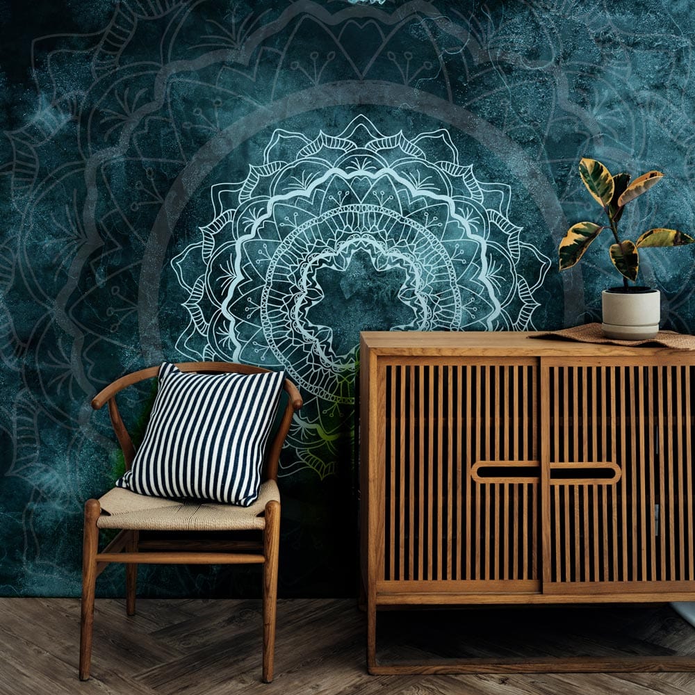 Teal Mandala Mist mural wallpaper with wood cabinet, chair, and navy cushion in contemporary living room.