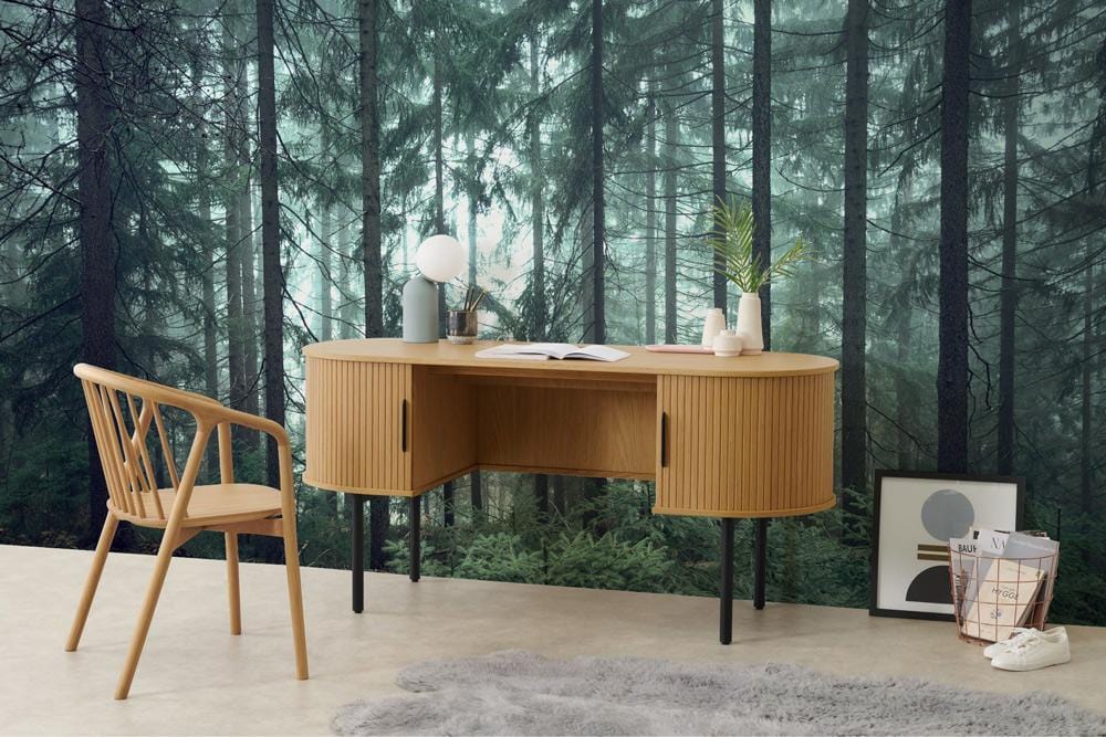 Wooden desk and chair with Enchanted Forest mural wallpaper, misty green woodland, grey rug, modern decor.