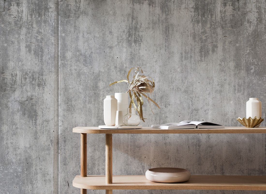 Industrial grey concrete effect mural wallpaper with wooden console table, modern interior design setting.
