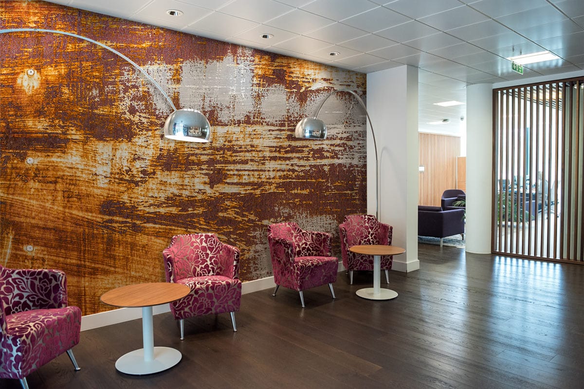 Industrial rustic wallpaper with vintage wood effect, textured brown and grey in modern lobby with chairs.