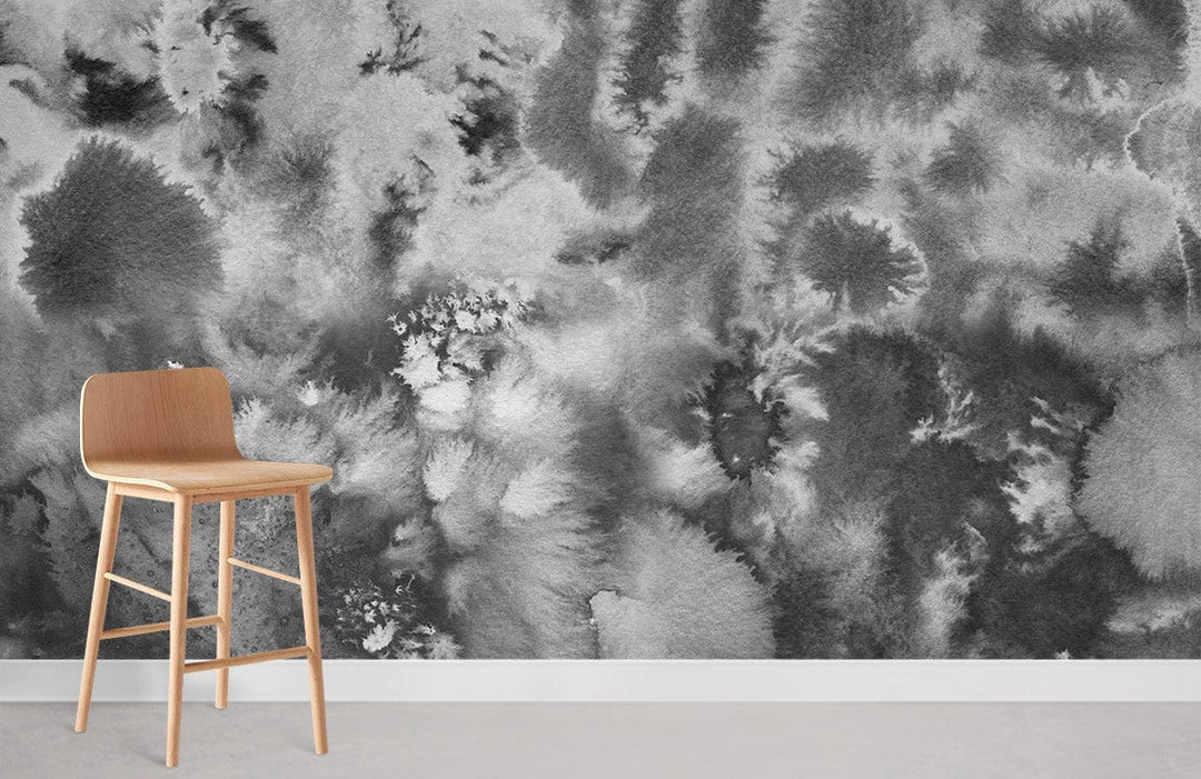 Monochrome watercolour cloudburst mural wallpaper in grey, wooden barstool on concrete floor, modern decor.