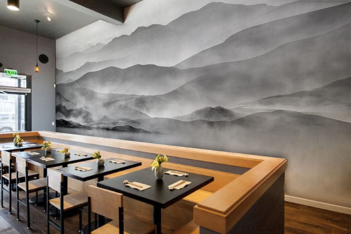 Monochrome misty mountain wallpaper in restaurant setting, wooden seating, black tables, grey tones.