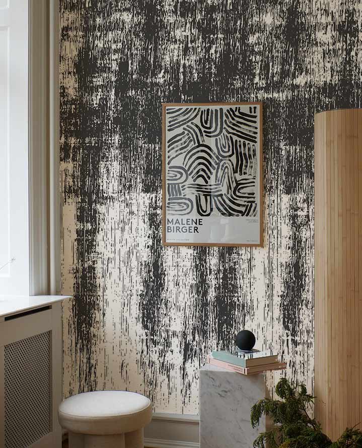 Grunge black and white textured wallpaper in modern living room with stool and artwork on wall.