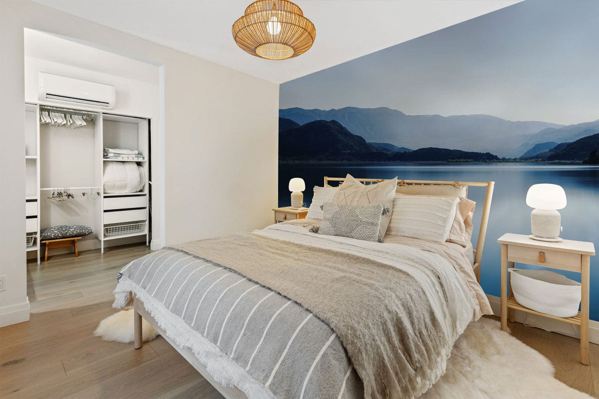 Bedroom with Peaceful Blue Lake Mountain Mural, neutral furnishings, wooden bed, serene atmosphere, soft lighting.