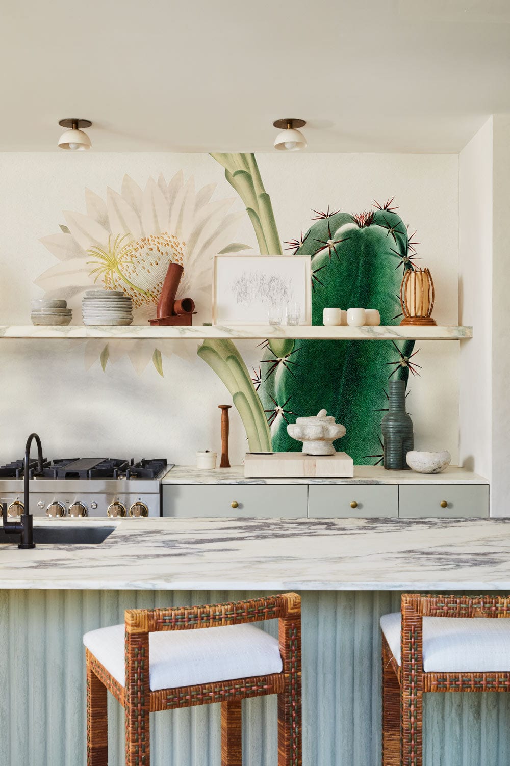Vintage botanical cactus wallpaper in modern kitchen with marble countertops and wicker chairs.