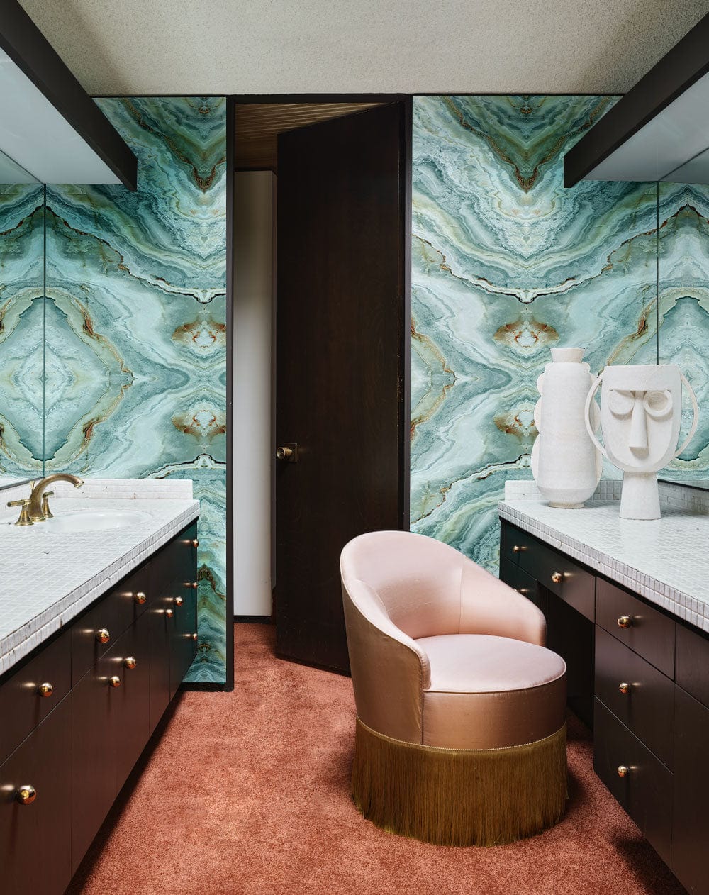 Elegant teal marble effect mural, bathroom with pink chair, brown cabinets, and plush carpet flooring.