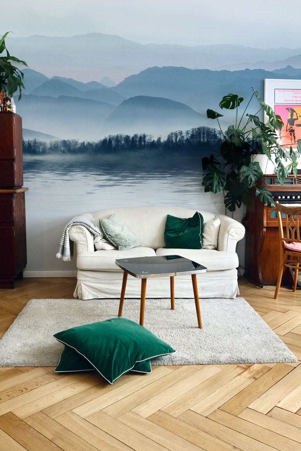 Serene Blue Misty Mountain Wallpaper with white sofa, wooden floor, green cushions in living room.