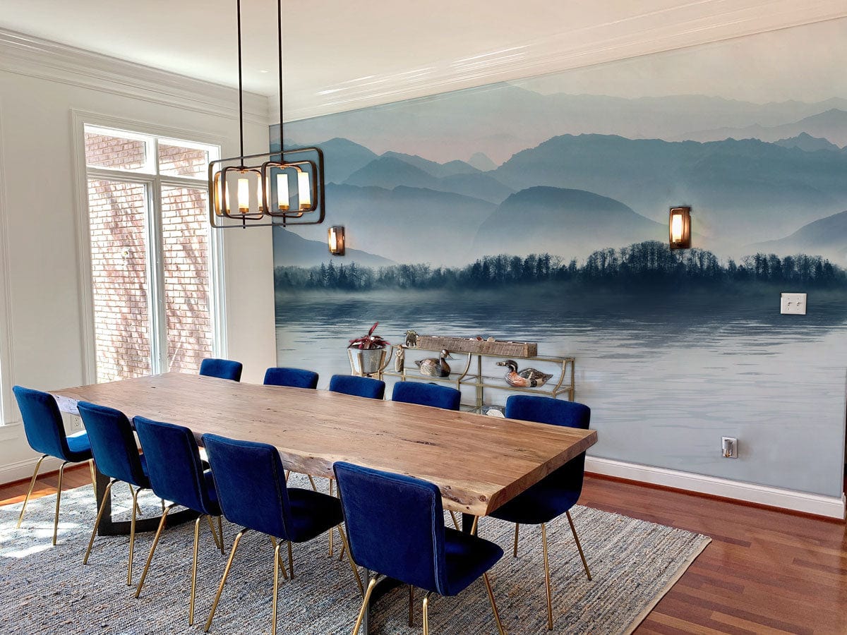 Serene Blue Misty Mountain mural wallpaper in dining room with wooden table, blue chairs, hardwood flooring.